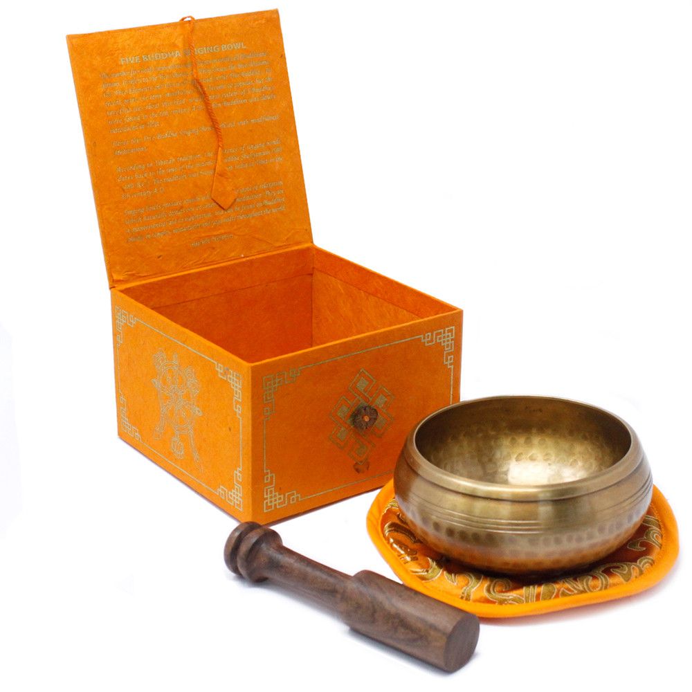 Brass singing bowl with wooden handle and orange box on a white background