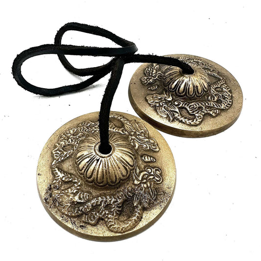 Summon strength, wisdom, and protection with these Tibetan Tingsha – Dragon Design, intricately handcrafted by skilled Tibetan artisans. Measuring approximately 7.4cm in diameter, each cymbal bears the majestic dragon motif, a powerful emblem of spiritual mastery and transformation.

When gently struck together, the Tingsha release a pure, resonant tone that clears stagnant energy and heightens focus — perfect for meditation, yoga, reiki, and ritual work. Beyond their spiritual use, they serve as exquisite 