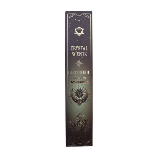 Cleanse your space with the crisp, herbal power of Arruda, a plant long revered for its protective and purifying qualities. This smudge incense set is paired with natural labradorite chipstones—stones of intuition, transformation, and shimmering mystique. Handcrafted in India using traditional smudge-style methods, each stick releases a clean, aromatic scent that brightens the atmosphere and restores energetic balance.

Inside the deep green celestial-themed sleeve, adorned with intricate artwork, you’ll fi