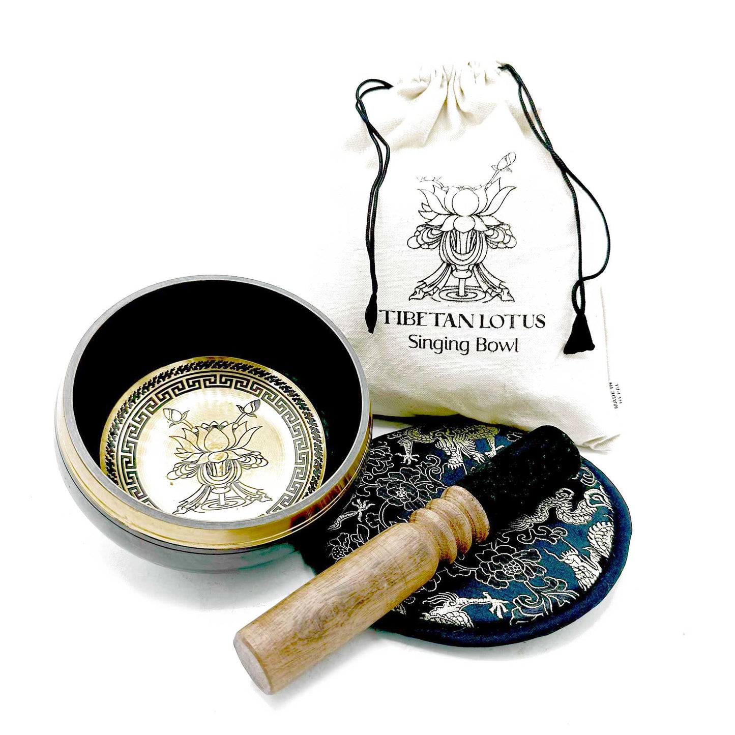 Tibetan singing bowl set with lid, cushion, and mallet on a white background