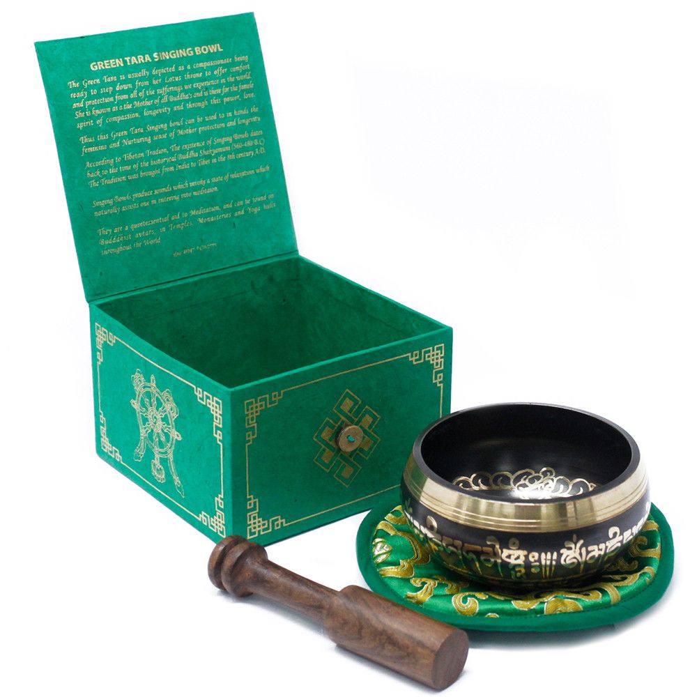 Tibetan singing bowl with wooden striker and green box on a white background