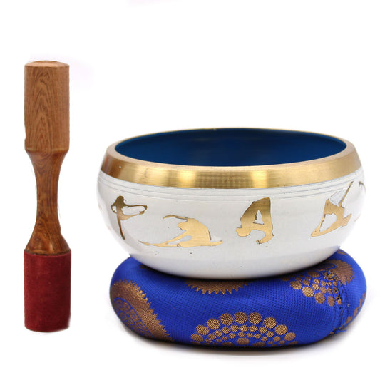 Tibetan singing bowl with gold figures and wooden striker on a white background