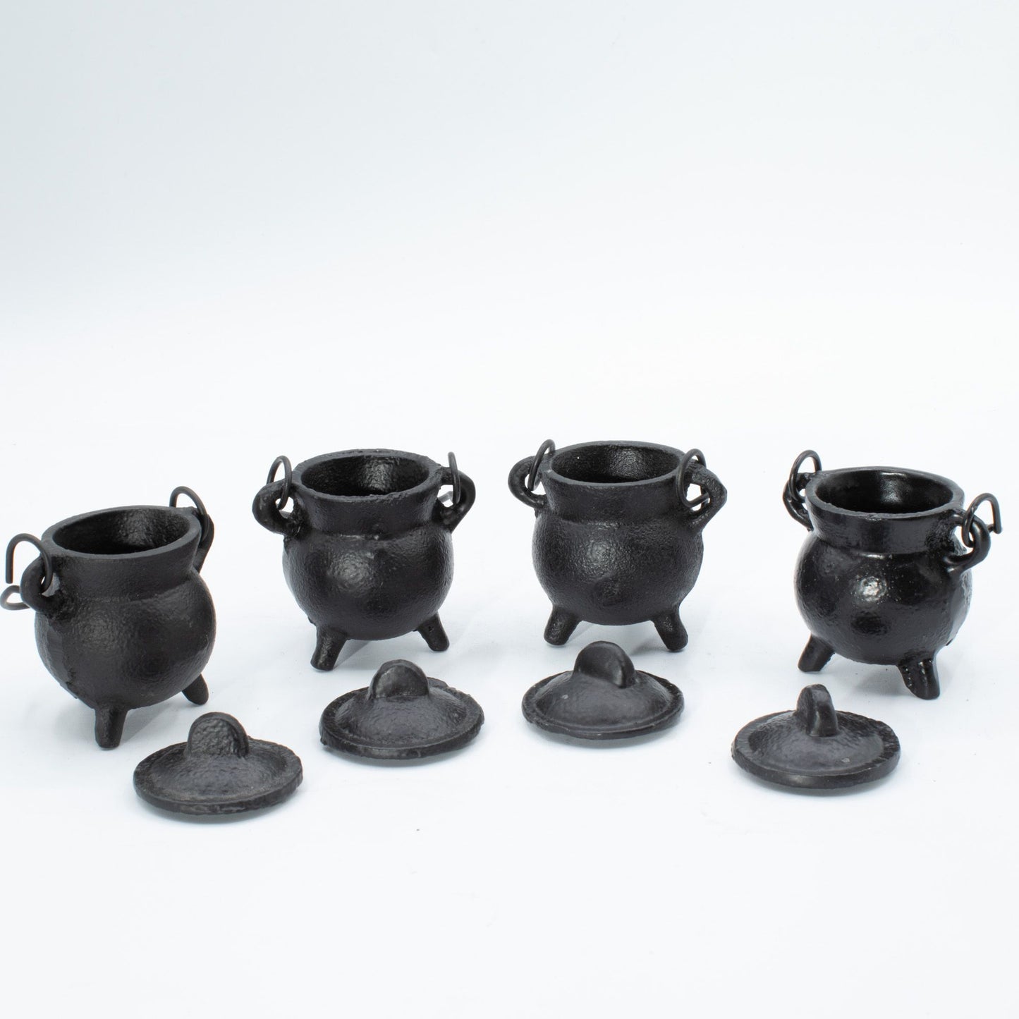 Small, simple, and brimming with gothic charm. This set of four extra small cast iron cauldrons captures the essence of witchy tradition in a perfectly petite size. Perfect for burning incense, herbs, or cones, they nestle beautifully on shelves, altars, or desks without demanding space. The sturdy three-leg base keeps them grounded and stable, while the fitted lid traps ash and contains the mystique. Each cauldron features a small handle for effortless repositioning between your sacred spaces. A versatile,