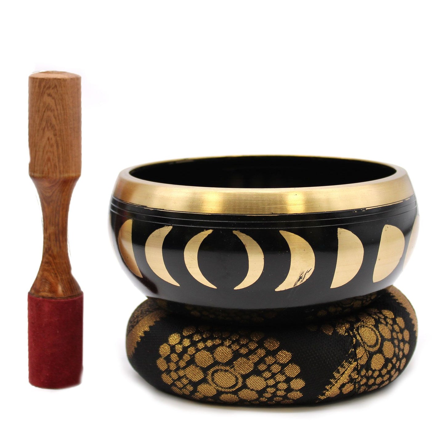 A black singing bowl with a gold rim and gold moon phase pattern, resting on a black cushion with gold floral detailing, next to a wooden mallet with a red velvet tip, on a white background.