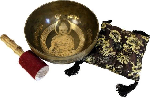 Tibetan singing bowl with Buddha design, mallet, and pouch on a white background