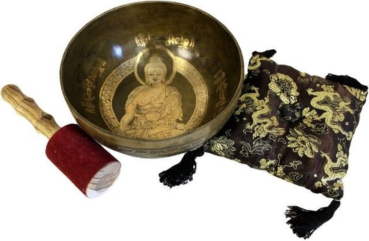 Tibetan singing bowl with Buddha design, mallet, and pouch on a white background