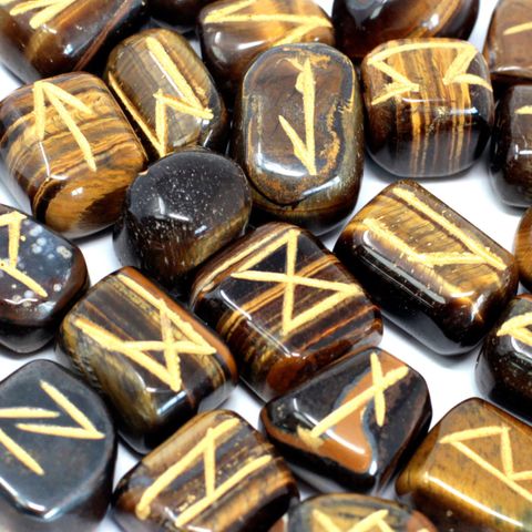 Unlock the ancient art of divination with this handcrafted Tiger Eye Rune Set, featuring 25 stones (24 engraved with rune symbols, 1 blank) nestled in a protective pouch. Each rune is carved from Tiger Eye, a powerful semi-precious stone known for its grounding, protective, and confidence-boosting properties. This shimmering golden-brown stone enhances mental clarity, helps with decision-making, and is often used to ward off negative energy. Ideal for spiritual seekers, beginners, or seasoned rune readers, 