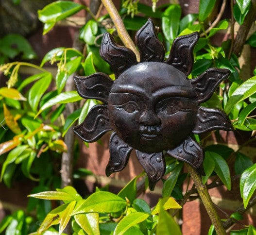 These deep brown resin casts depict a cheery sun face.&nbsp; To make these beautiful resin figures, a wax original is carefully hand carved and then made into a mold. Into this the craftsmen are then able to pour the resin and create these wonderful plaques.