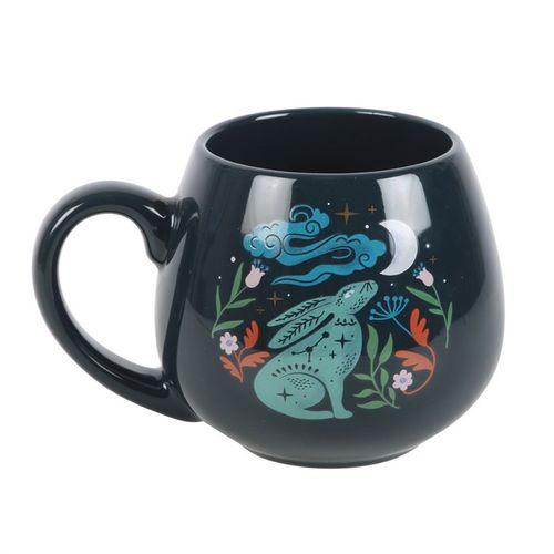 Black mug with a colorful design of a creature, flowers, and celestial elements on a white background