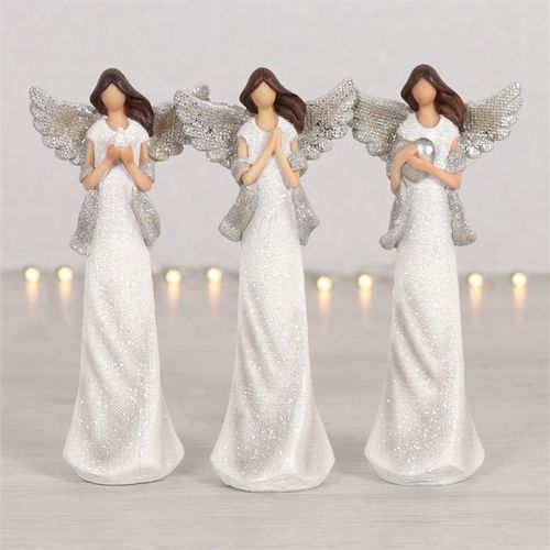 Three angel figurines with silver wings and white dresses on a neutral background